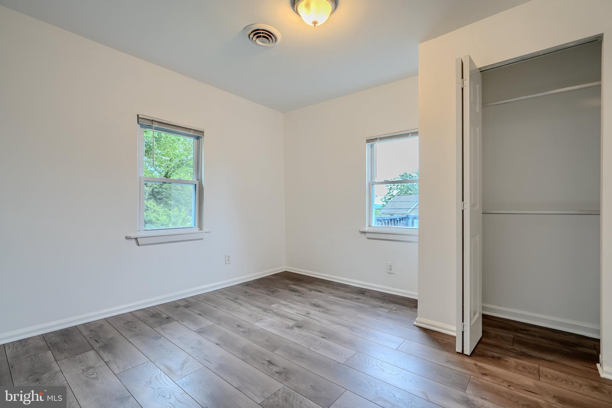 227 Elizabeth Avenue Baltimore, MD 21225 - Photo 22 of 31 an empty room with wooden floor and windows