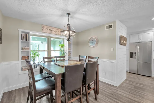 a large white kitchen with a center island wooden floor and stainless steel appliances