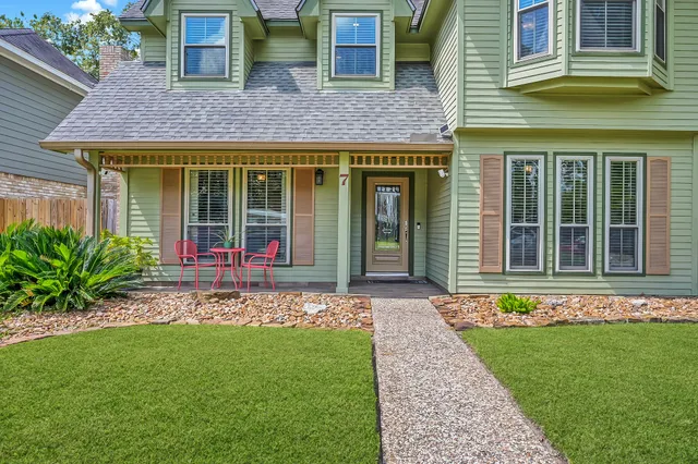 a view of a brick house with a large windows plants and large tree