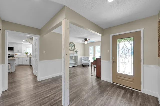 a view of a hallway with wooden floor and a living room