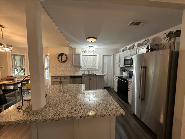 a large kitchen with granite countertop a stove a sink and a refrigerator