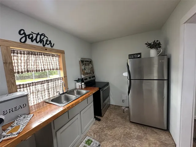 a kitchen with stainless steel appliances granite countertop a refrigerator a stove a sink and white cabinets