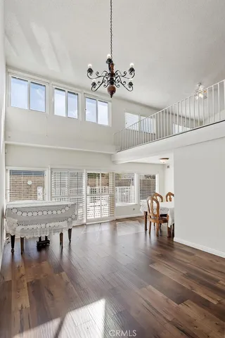 a dining room with wooden floor a chandelier a wooden table and chairs