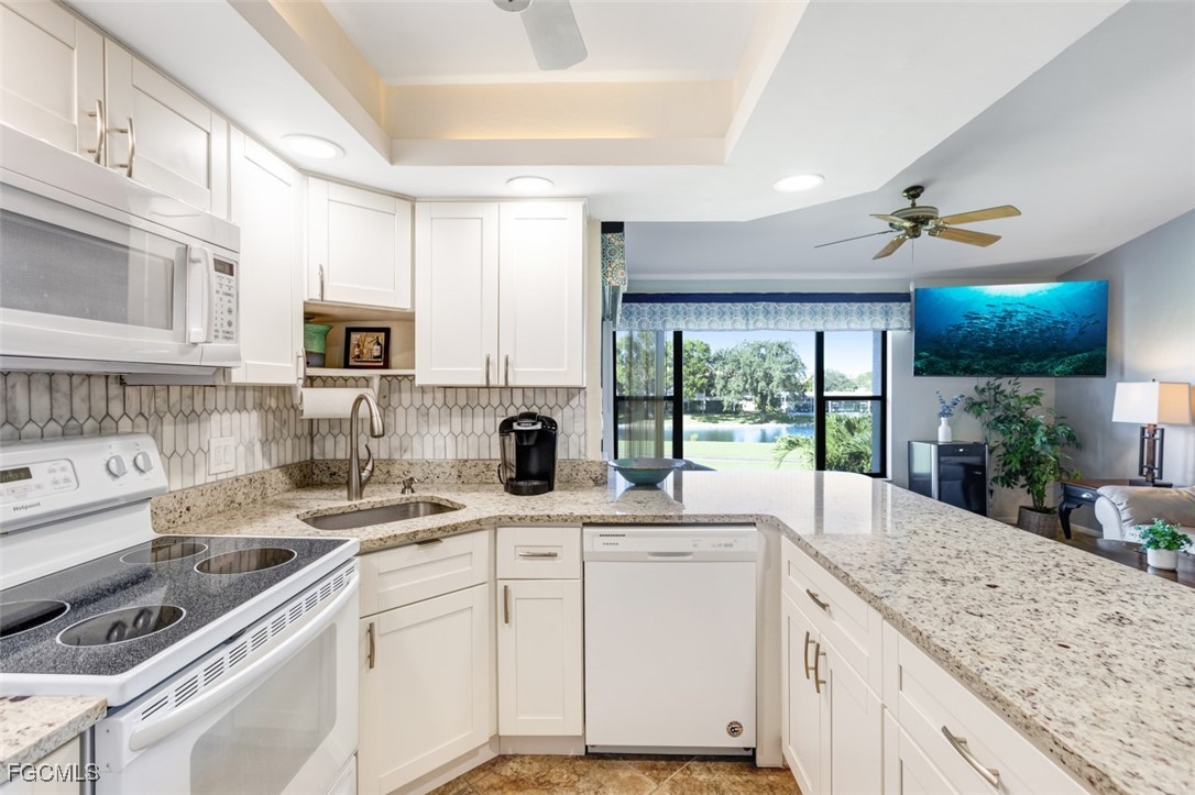 5710 Trailwinds Drive, Unit 525 Fort Myers, FL 33907 - Photo 11 of 37 a kitchen with granite countertop a sink stainless steel appliances and white cabinets