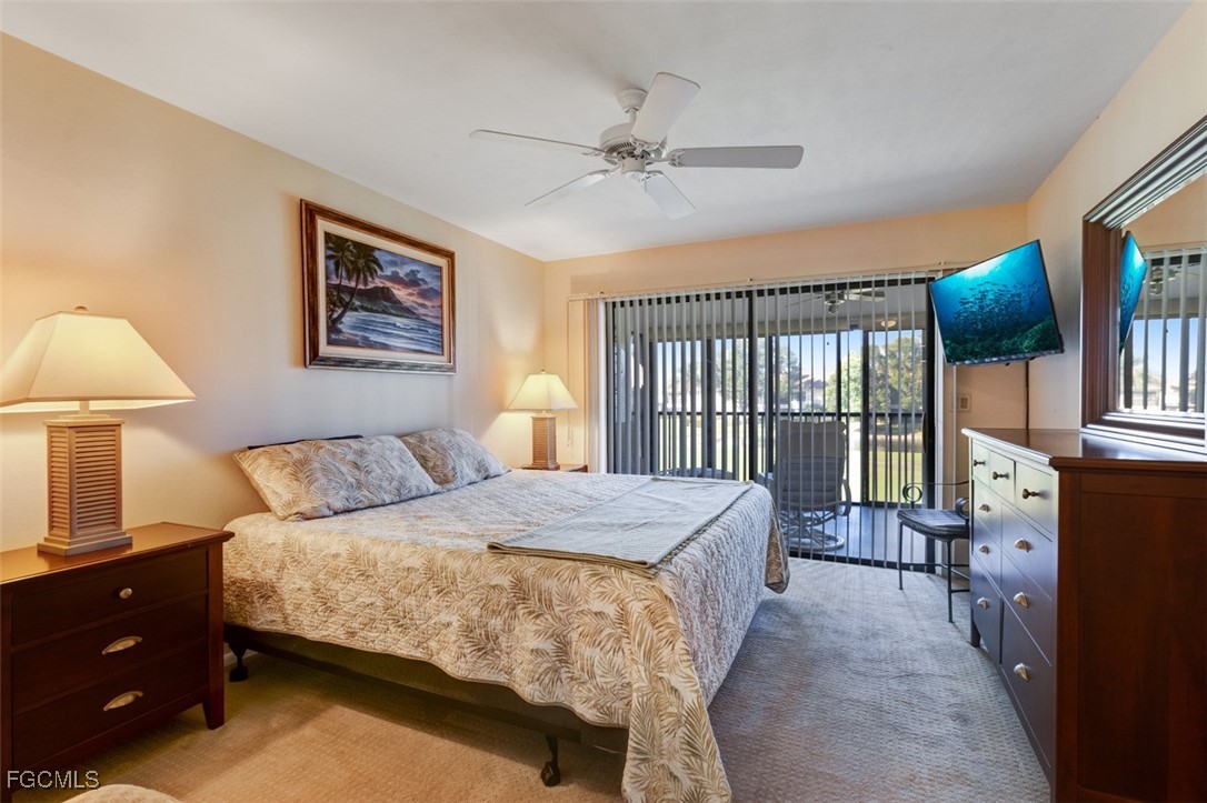 5710 Trailwinds Drive, Unit 525 Fort Myers, FL 33907 - Photo 14 of 37 a bedroom with a bed a lamp and a large window