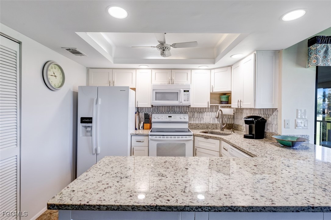5710 Trailwinds Drive, Unit 525 Fort Myers, FL 33907 - Photo 8 of 37 a kitchen with stainless steel appliances granite countertop a refrigerator oven stove a sink dishwasher and white cabinets with wooden floor