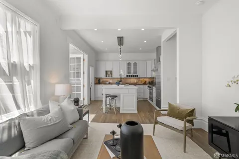 a kitchen with kitchen island a dining table chairs and white cabinets
