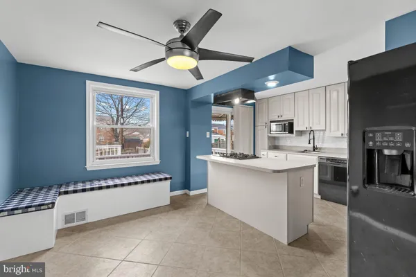 a kitchen with stainless steel appliances kitchen island granite countertop a refrigerator oven a sink a dining table and chairs with wooden floor