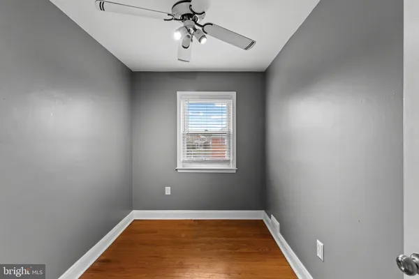 an empty room with a window and a chandelier fan