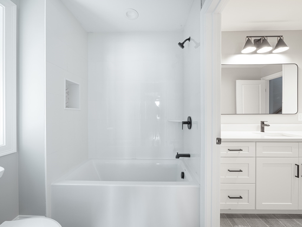 5 Stanley Street Natick, MA 01760 - Photo 15 of 21 a bathroom with a bathtub a sink a toilet and a mirror