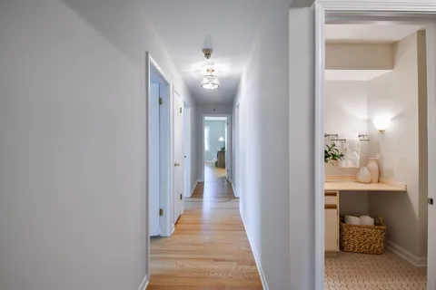 a view of a hallway with a livingroom and a chandelier fan wooden floor and a chandelier