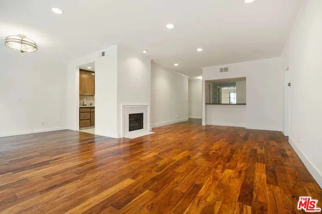 a view of empty room with wooden floor and fireplace
