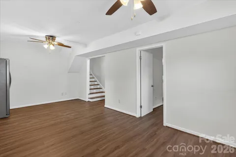 an empty room with wooden floor ceiling fan and window