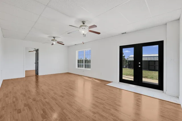 a view of an empty room with a window and kitchen view