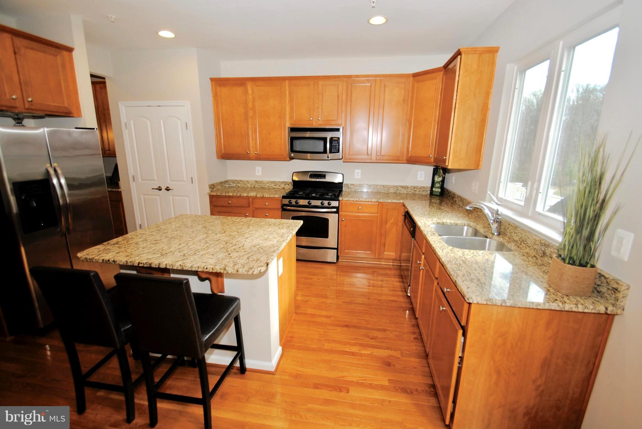 2707 Amber Crest Road Hanover, MD 21076 - Photo 4 of 30 a kitchen with stainless steel appliances granite countertop a stove a sink a microwave a refrigerator white cabinets and wooden floor