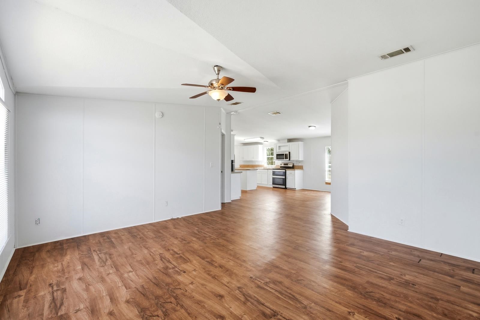 299 Cayenne Street Interlachen, FL 32148 - Photo 11 of 73 Unfurnished living room with dark wood-style floors, ceiling fan, and lofted ceiling