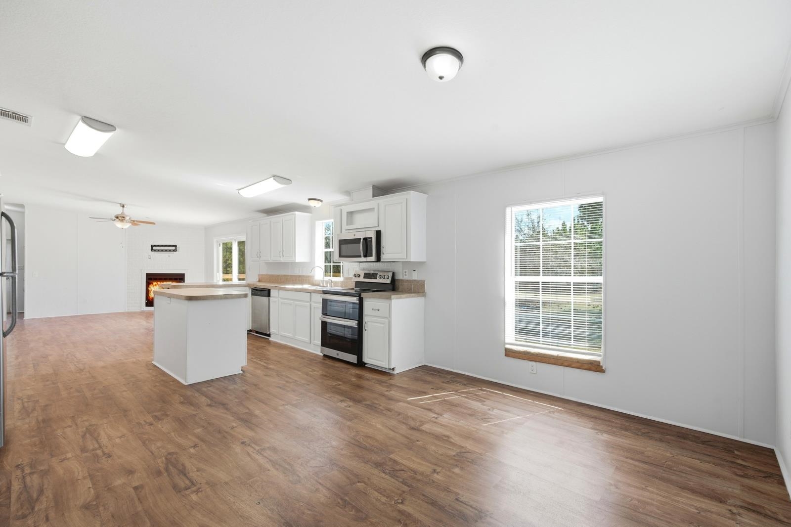 299 Cayenne Street Interlachen, FL 32148 - Photo 73 of 73 Kitchen with stainless steel appliances, light countertops, a lit fireplace, open floor plan, and white cabinets