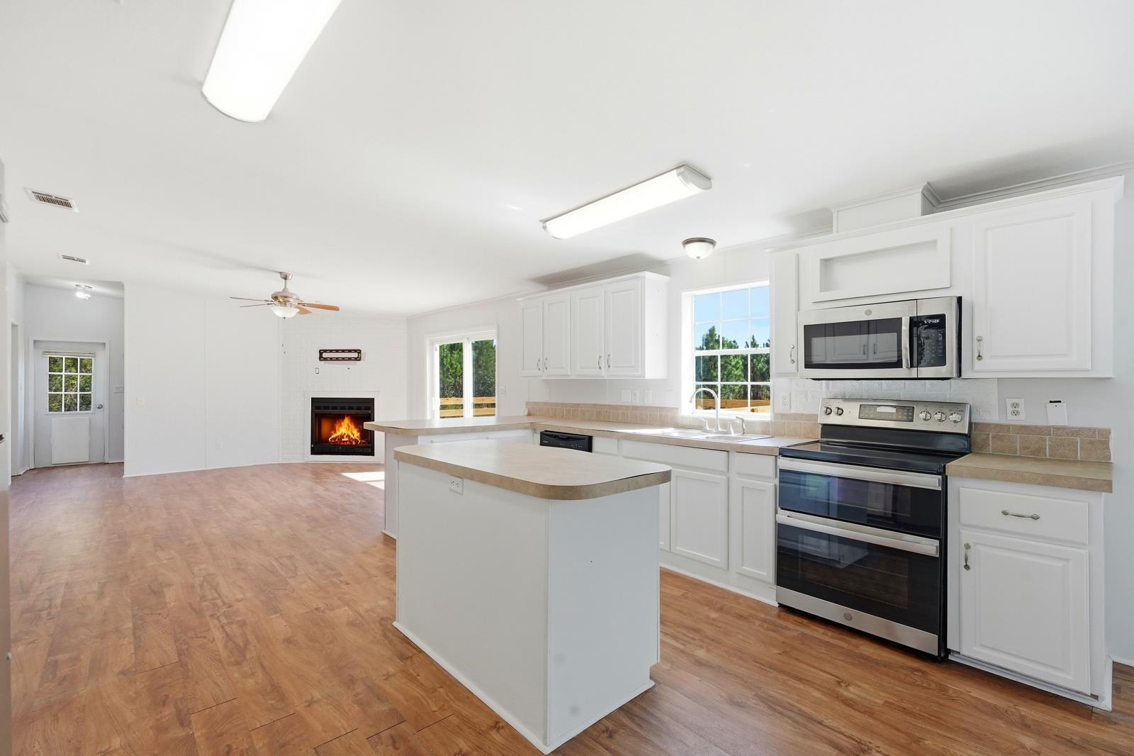 299 Cayenne Street Interlachen, FL 32148 - Photo 15 of 73 Kitchen featuring a warm lit fireplace, stainless steel appliances, light countertops, white cabinets, and a center island