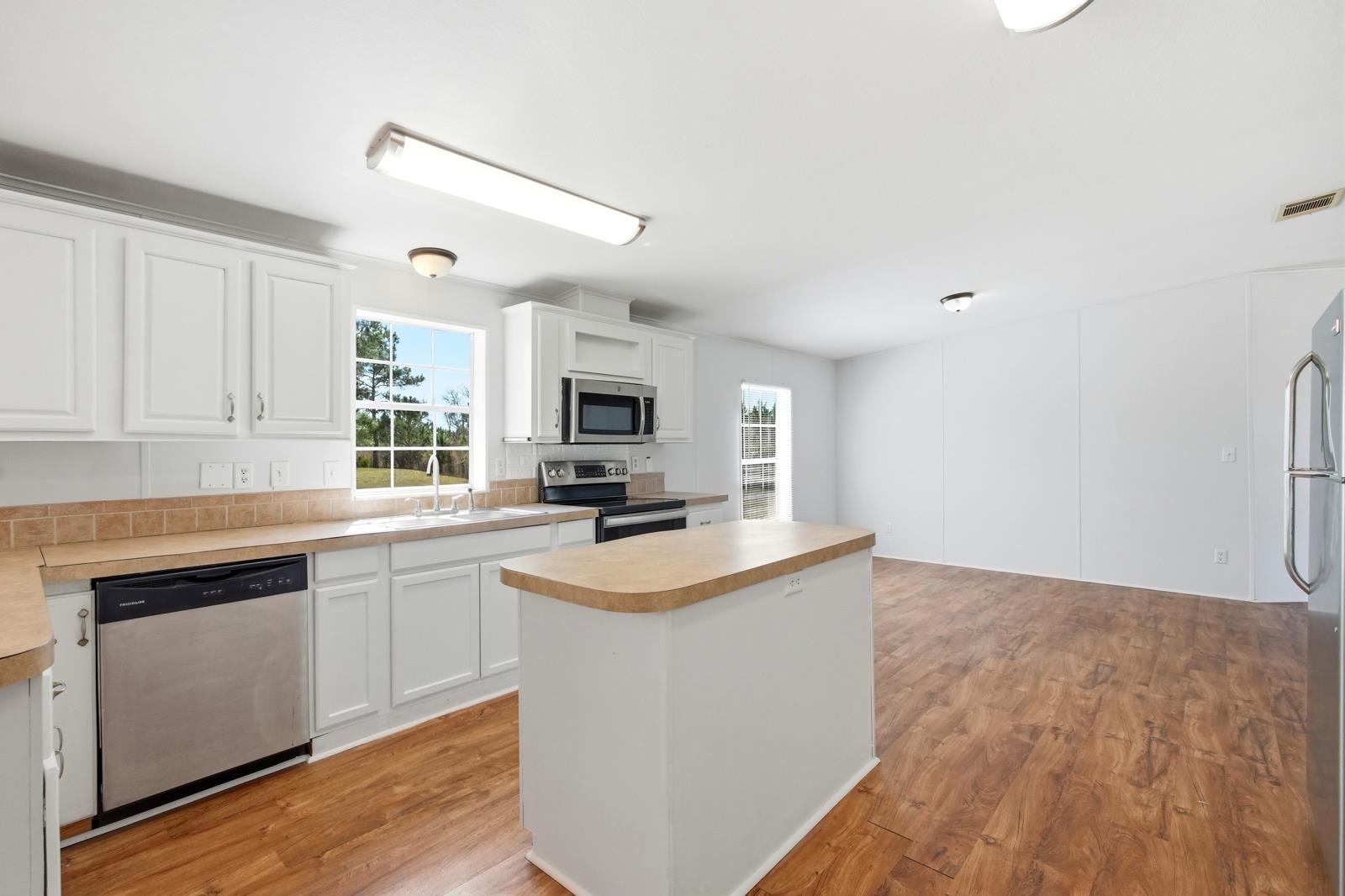 299 Cayenne Street Interlachen, FL 32148 - Photo 16 of 73 Kitchen with stainless steel appliances, a kitchen island, white cabinets, light wood-style flooring, and light countertops