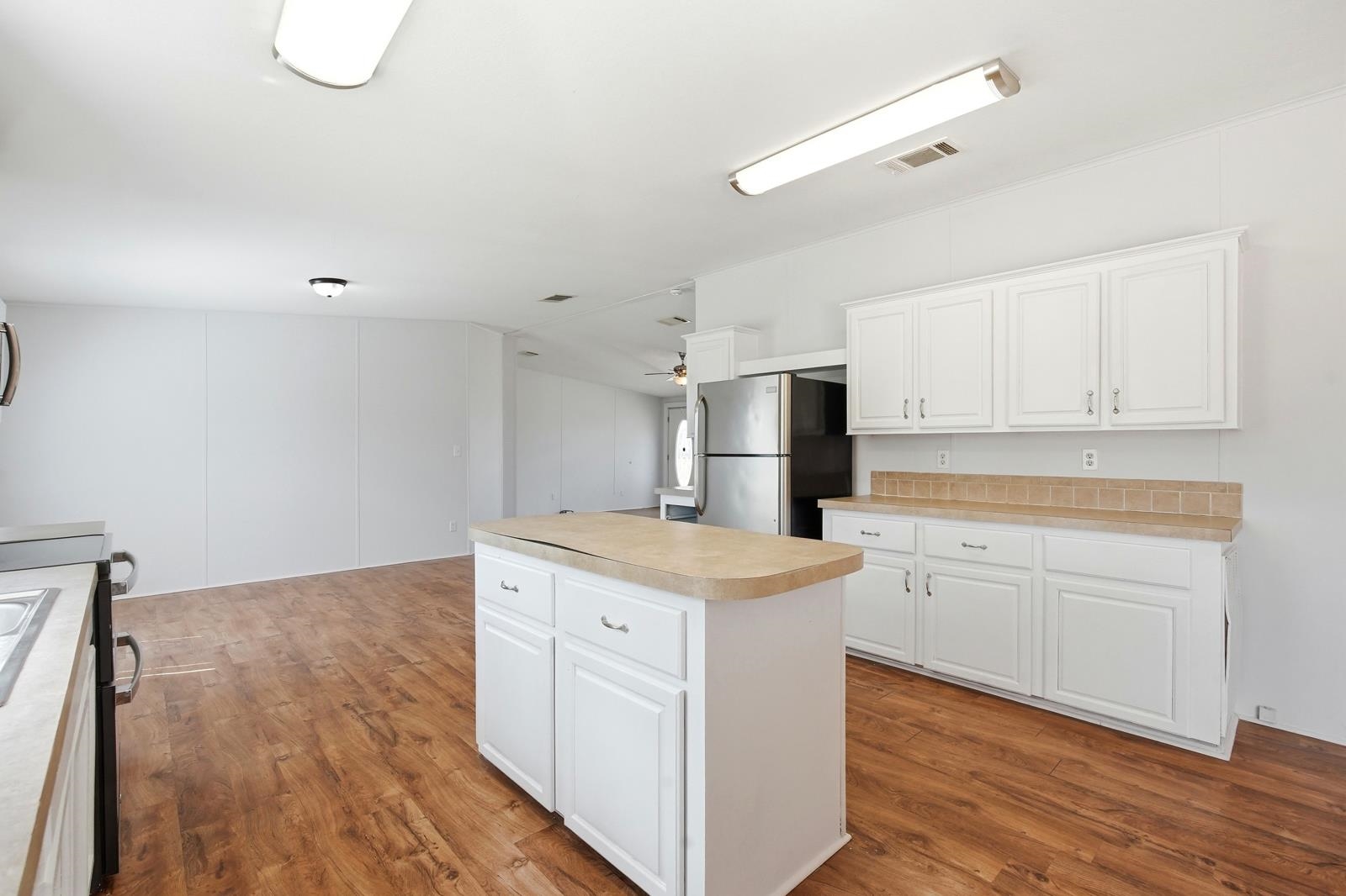 299 Cayenne Street Interlachen, FL 32148 - Photo 17 of 73 Kitchen with a center island, freestanding refrigerator, white cabinets, light countertops, and light wood-style flooring