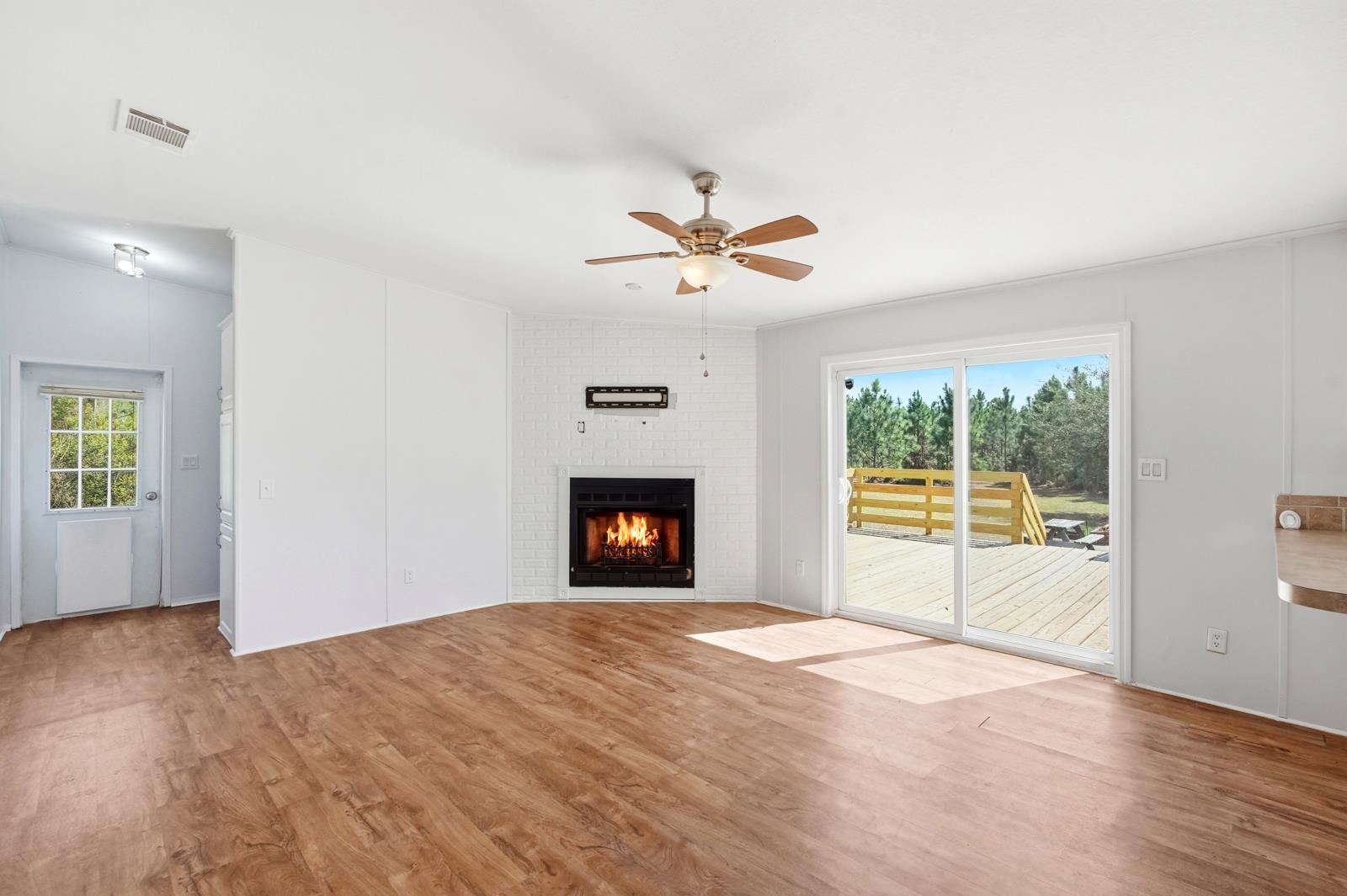 299 Cayenne Street Interlachen, FL 32148 - Photo 20 of 73 Unfurnished living room featuring light wood-type flooring, a ceiling fan, a fireplace, and plenty of natural light
