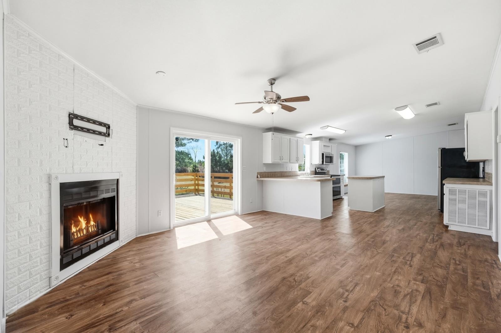 299 Cayenne Street Interlachen, FL 32148 - Photo 21 of 73 Unfurnished living room featuring dark wood-style floors, ceiling fan, and a brick fireplace