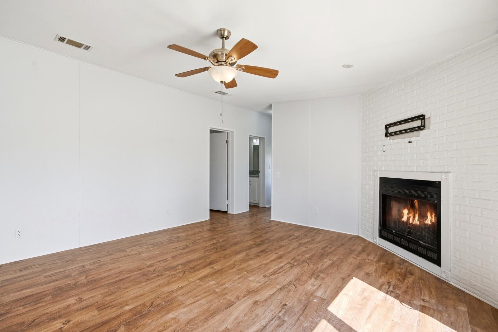 299 Cayenne Street Interlachen, FL 32148 - Photo 22 of 73 Unfurnished living room with ceiling fan, light wood-type flooring, and a brick fireplace