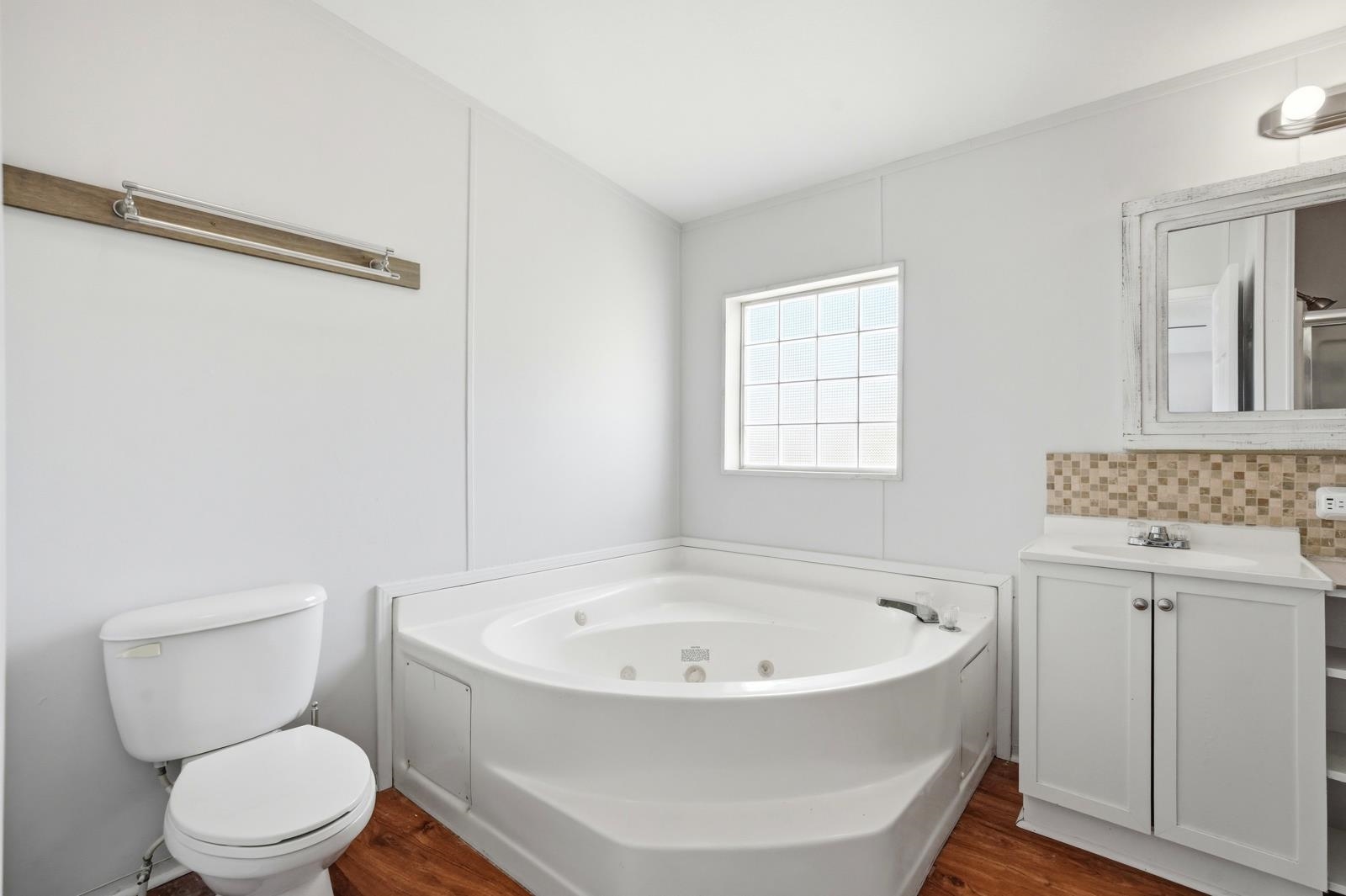 299 Cayenne Street Interlachen, FL 32148 - Photo 25 of 73 Full bath featuring vanity, a jetted tub, dark wood-style flooring, and backsplash