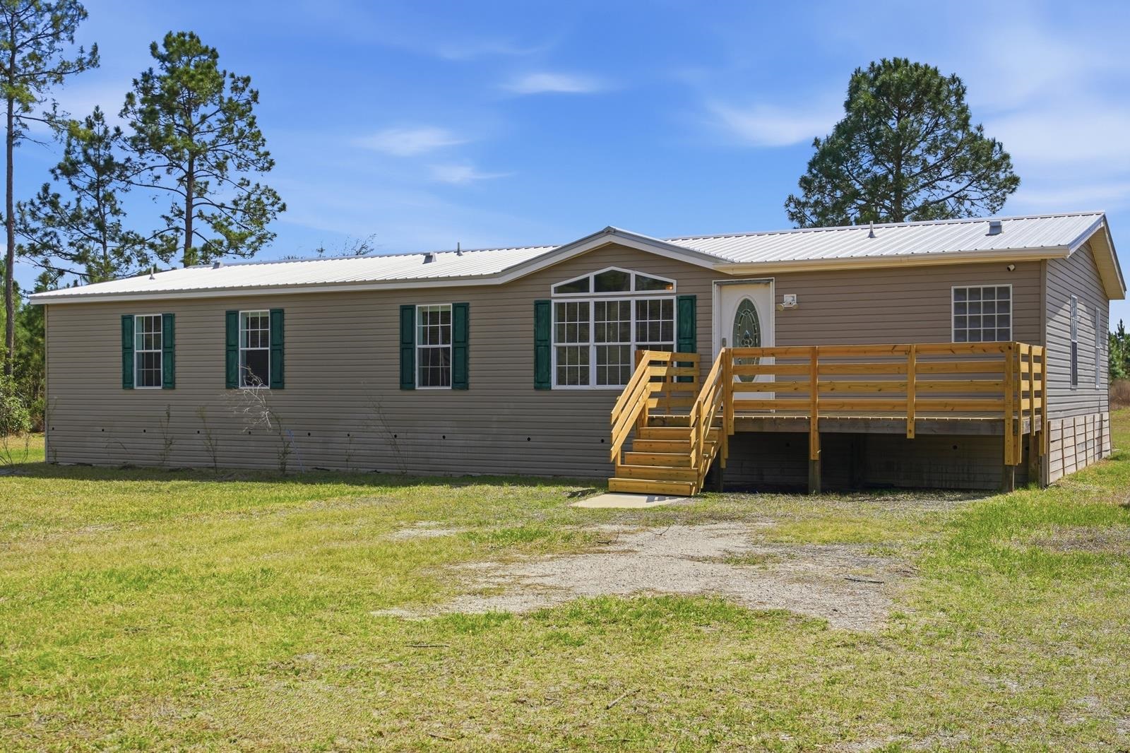 299 Cayenne Street Interlachen, FL 32148 - Photo 3 of 73 Rear view of property with a metal roof, a yard, and a wooden deck