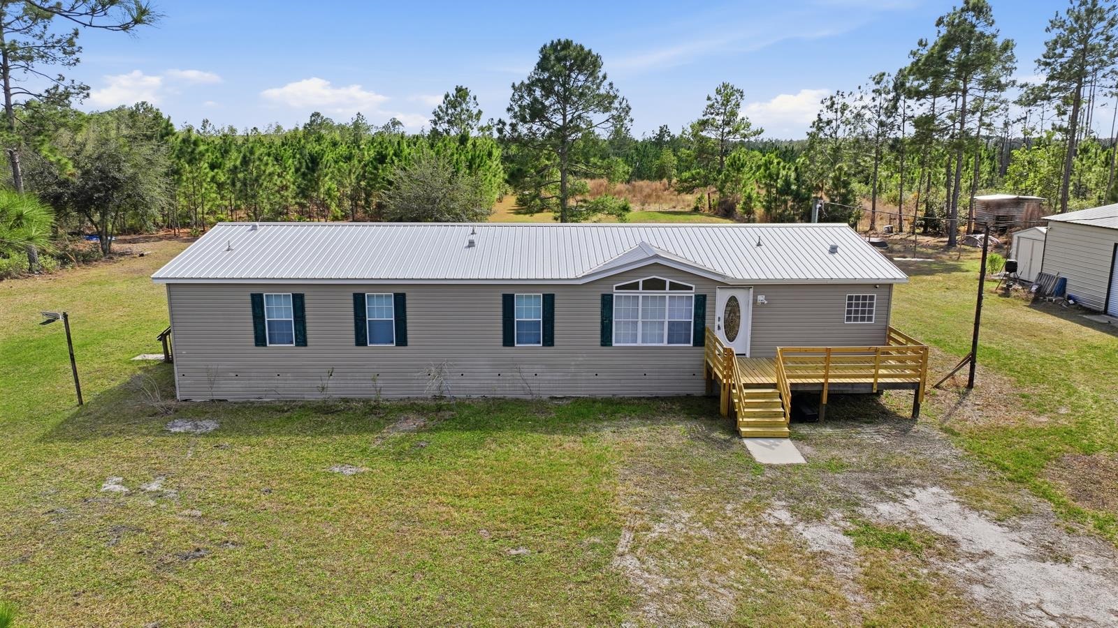 299 Cayenne Street Interlachen, FL 32148 - Photo 63 of 73 View of front of home featuring a metal roof, a front yard, and a wooden deck
