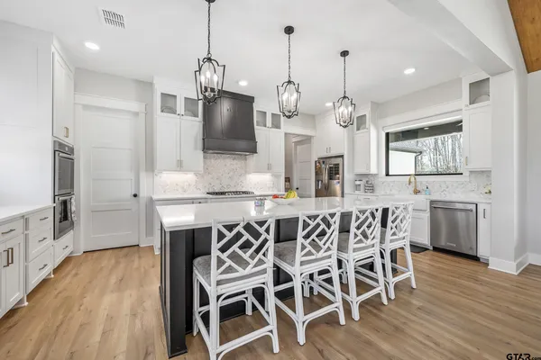 a kitchen with stainless steel appliances kitchen island granite countertop a dining table chairs and granite counter tops