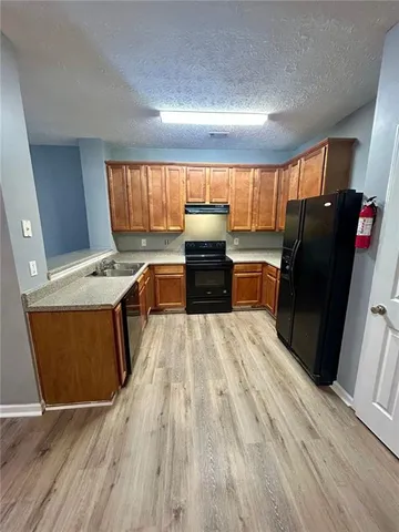 a kitchen with granite countertop a refrigerator stove top oven and sink
