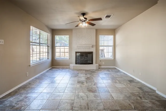 a view of an empty room with a fireplace and a window