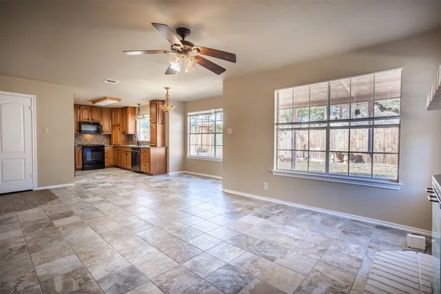 a view of a livingroom with a ceiling fan windows and kitchen view