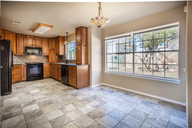 a view of kitchen with stainless steel appliances granite countertop a stove top oven a sink dishwasher a refrigerator and black cabinets next to a window