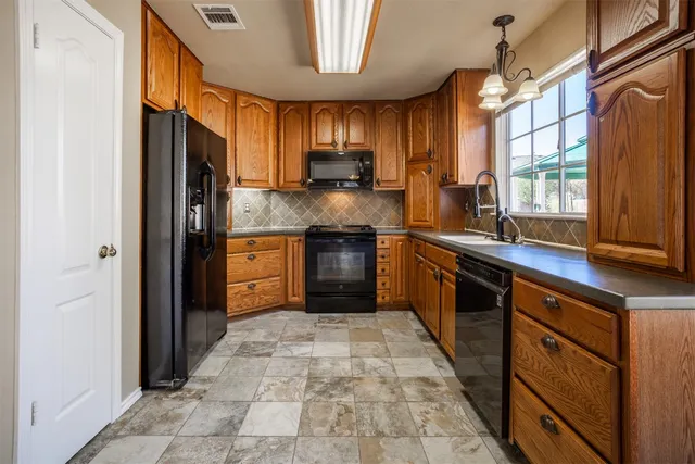 a kitchen with stainless steel appliances granite countertop a refrigerator a sink dishwasher a stove top oven a refrigerator and dishwasher