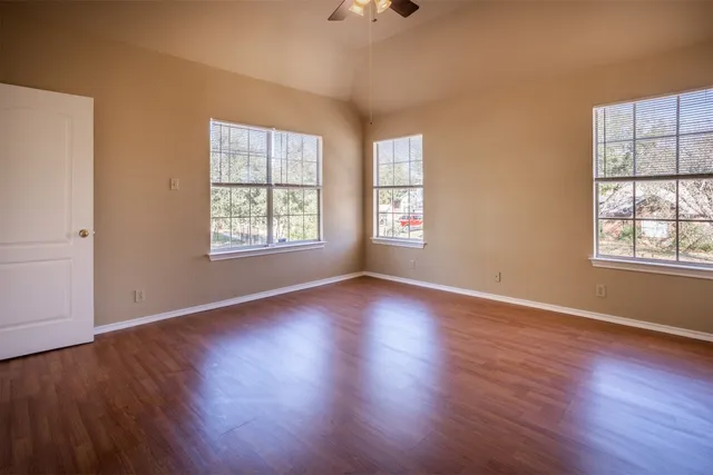 an empty room with wooden floor and windows