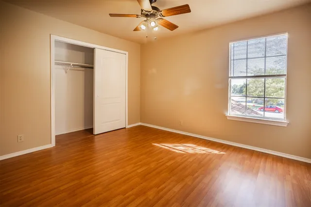 an empty room with wooden floor closet and windows