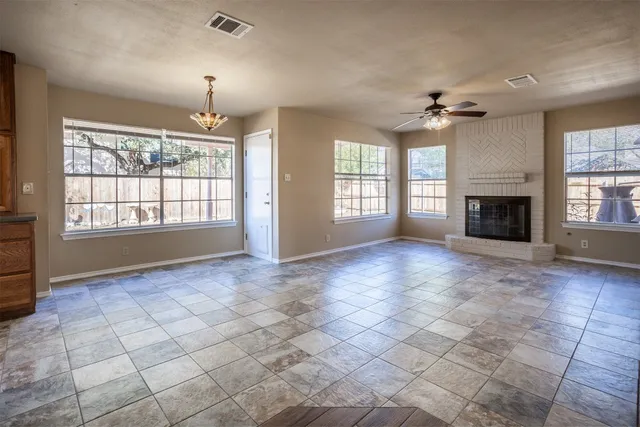 an empty room with windows and fireplace