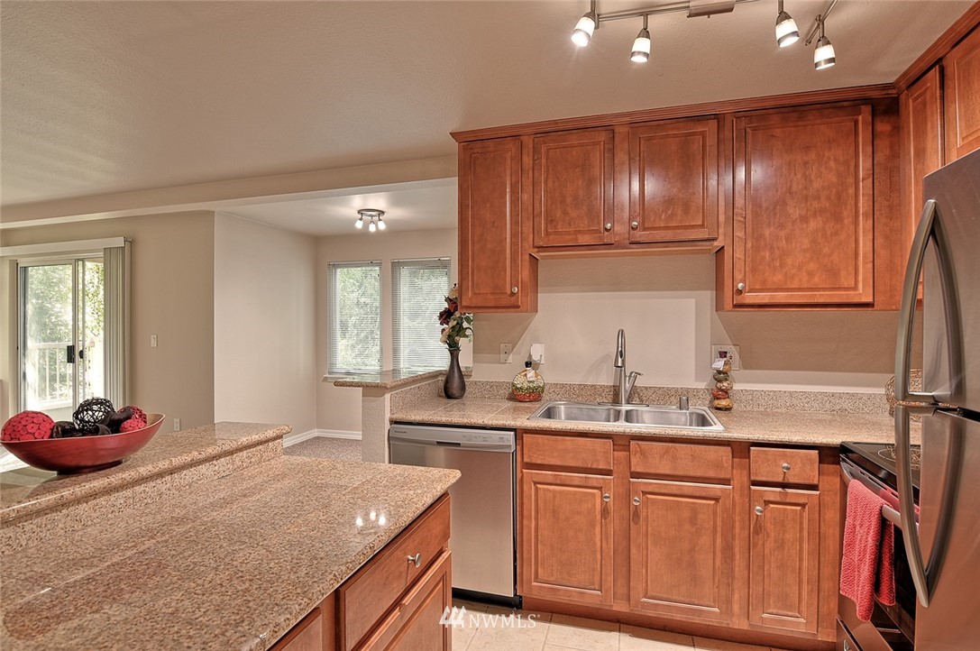 20330 Bothell Everett Highway, Unit C204 Bothell, WA 98012 - Photo 3 of 24 a kitchen with kitchen island granite countertop wooden cabinets and white appliances