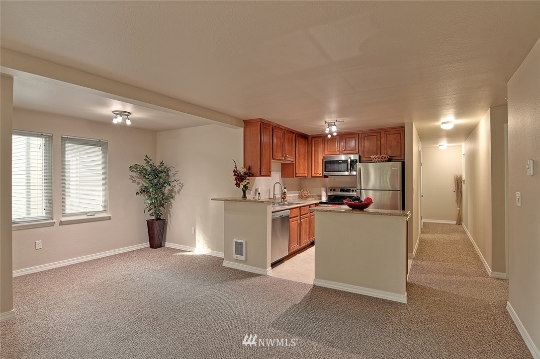 20330 Bothell Everett Highway, Unit C204 Bothell, WA 98012 - Photo 7 of 24 a kitchen with stainless steel appliances kitchen island granite countertop a refrigerator a stove a sink dishwasher and white cabinets with wooden floor