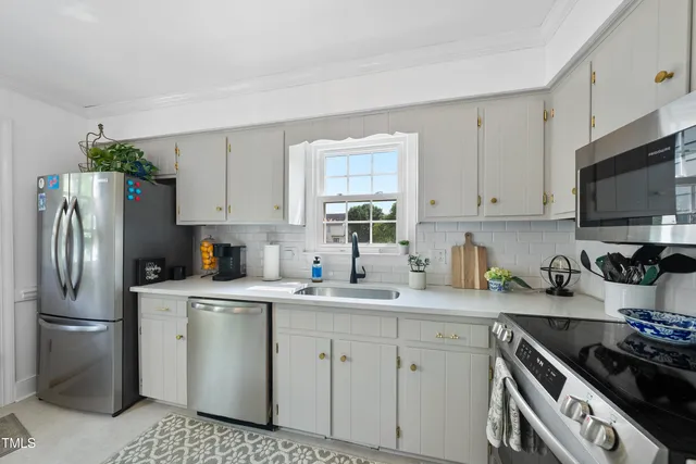 a kitchen with a sink dishwasher a stove a microwave oven and a dining table with wooden floor