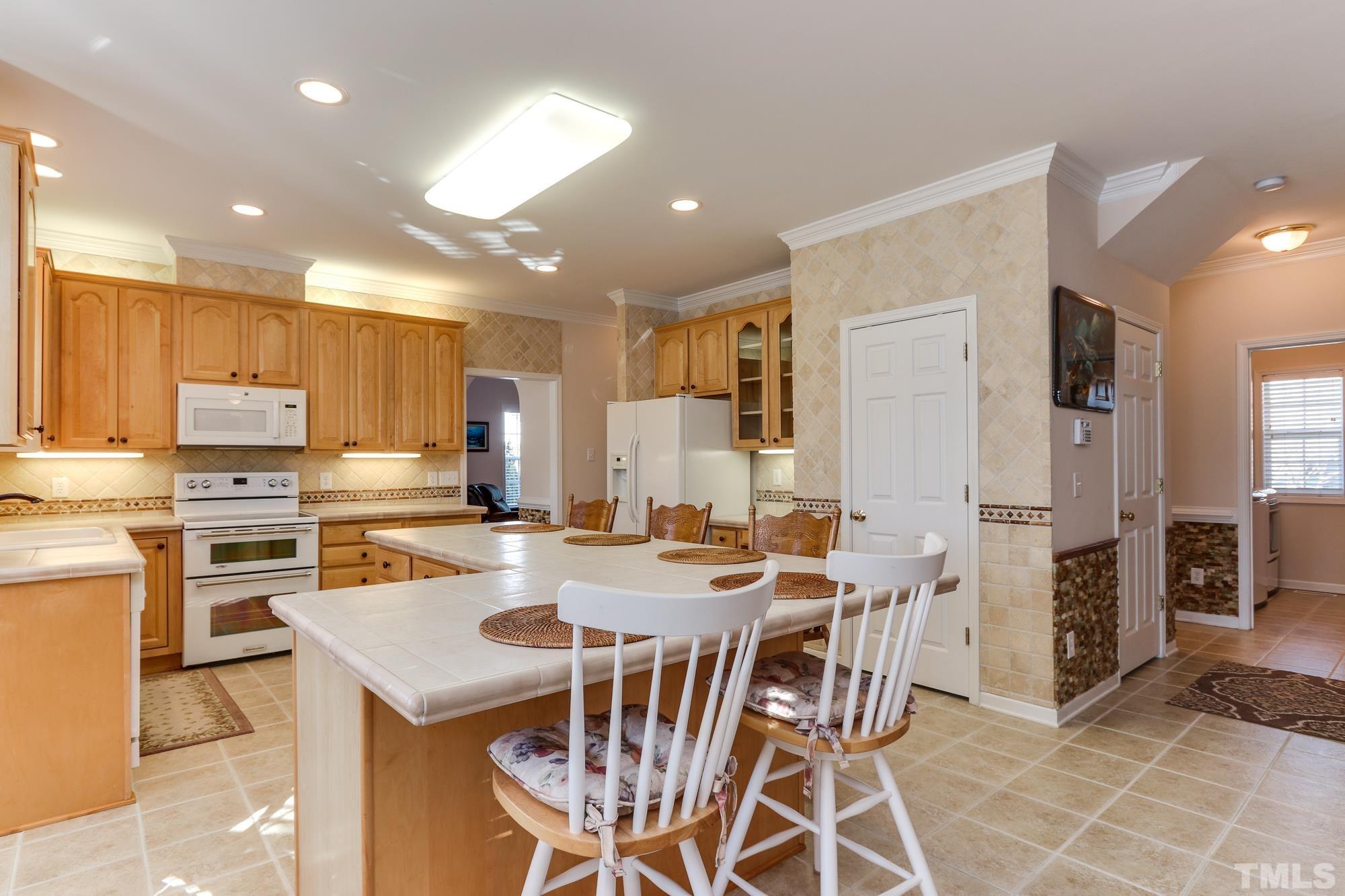 100 Mickleson Ridge Drive Raleigh, NC 27603 - Photo 15 of 59 a kitchen with stainless steel appliances kitchen island granite countertop a kitchen island and chairs in it