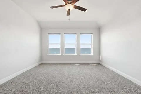 an empty room with chandelier fan and windows