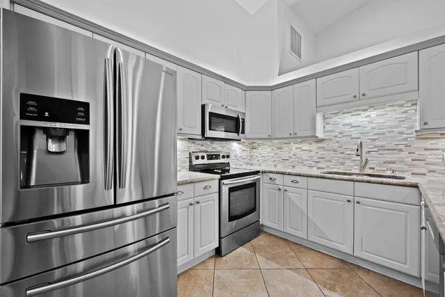 a kitchen with granite countertop stainless steel appliances and refrigerator