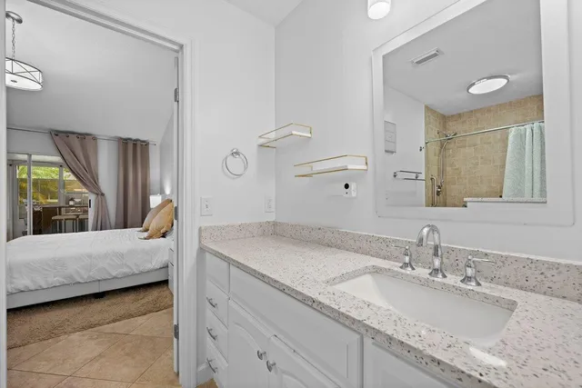 a en suite bathroom with a granite countertop sink and a mirror