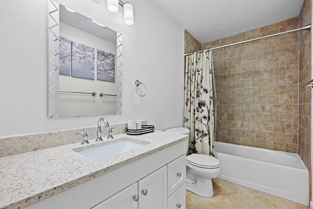a bathroom with a granite countertop sink a toilet and shower
