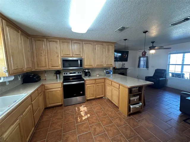 a kitchen with granite countertop a stove top oven a sink dishwasher and a refrigerator