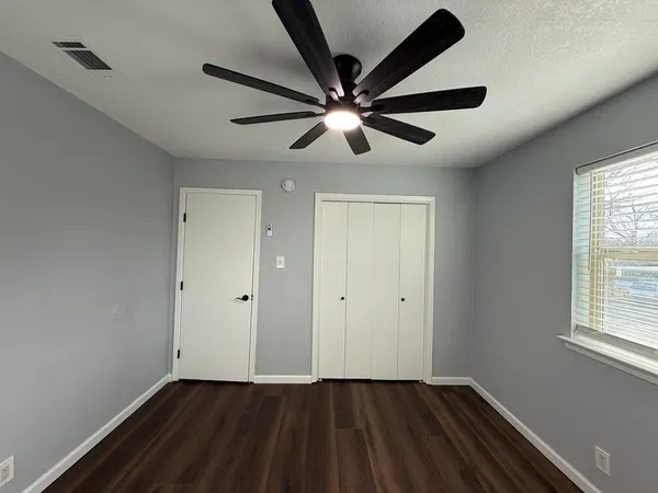a view of an empty room with wooden floor and a window