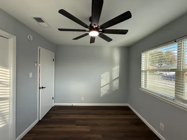 a view of an empty room with wooden floor and a window